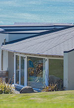 Impact Roofing - thumbnail image of a house by the sea roofed by Impact